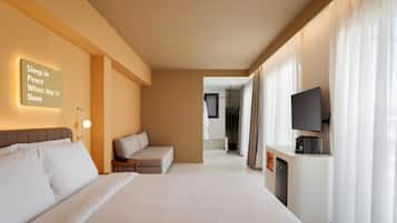 Una habitación de hotel con cama, sofá, televisor y cafetera.