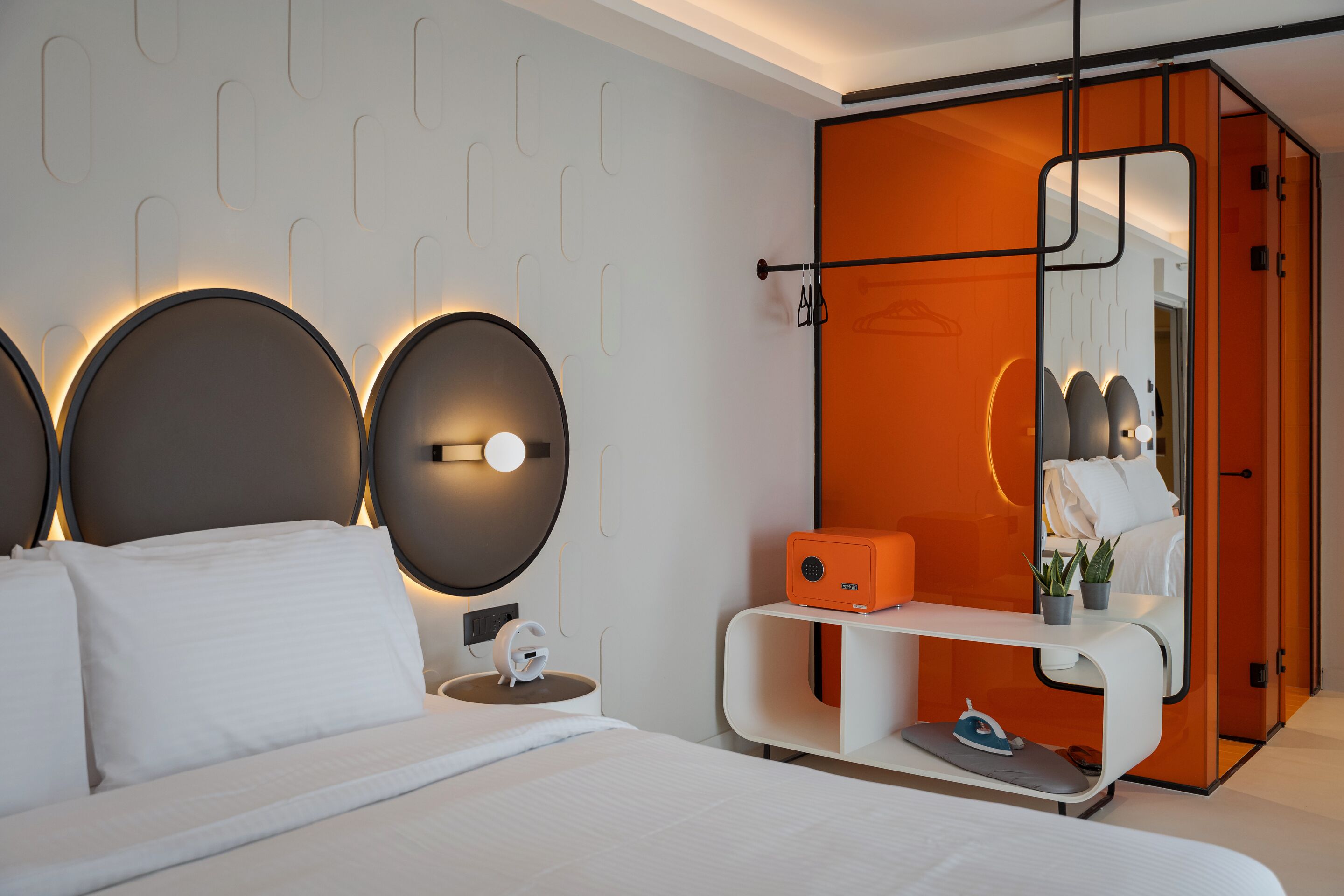 A modern bedroom with a bed, bedside tables, a nightstand, a mirror, and a wardrobe.