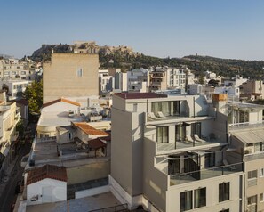 A modern urban landscape with a mix of residential and commercial buildings, featuring flat-roofed structures and a prominent historical site in the background.