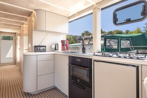 A compact kitchenette with a Bosch coffee maker, a small oven, and a window overlooking a green area.