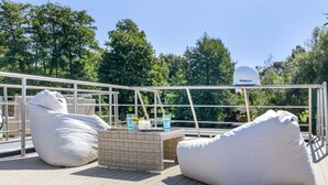 A rooftop terrace with outdoor seating, a security camera, and a view of trees.