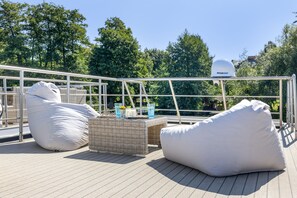 A rooftop terrace with outdoor seating, a security camera, and a view of trees.