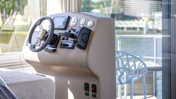A boat's control panel with a steering wheel, gauges, and various controls.
