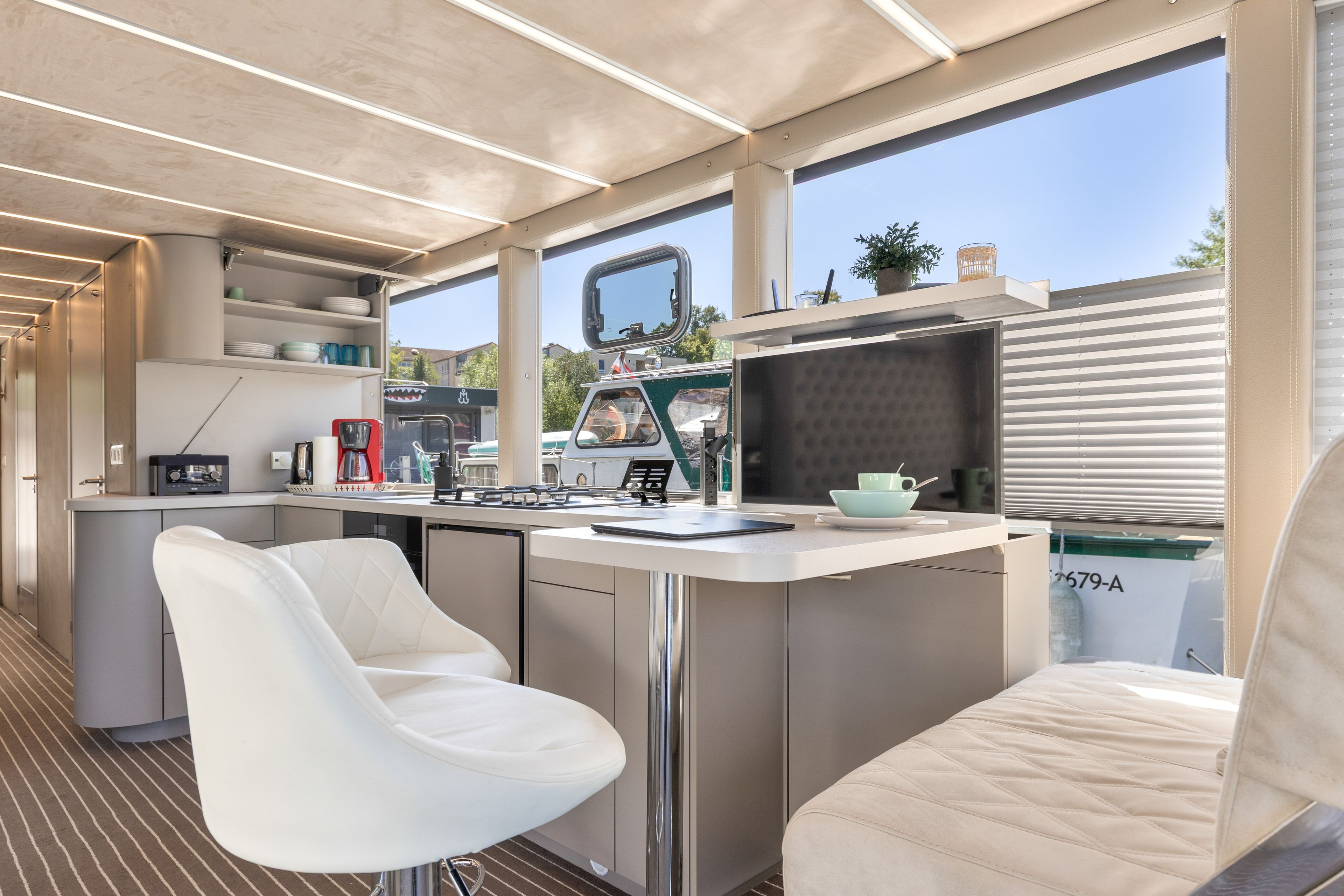 Eine moderne Küche mit Barbereich, weißen Barhocker und Blick ins Freie.