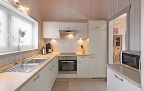 Een moderne keuken met witte kastjes, roestvrijstalen apparatuur en een betegelde vloer.