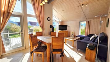 Ein holzmöbliertes Wohnzimmer mit einer Couch, einem Fernseher und einem Essbereich mit Stühlen und einem Tisch.