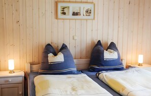 A room with two beds, each with a pillow and a bedside lamp.