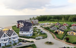 A residential area with houses, a roundabout, and a body of water in the background.