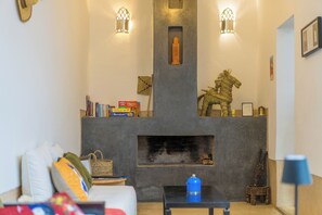 A living room with a fireplace, books, and decorative items. - RIAD DAR NKOB - A charming, private riad right in the heart of the Medina (Marrakesh)