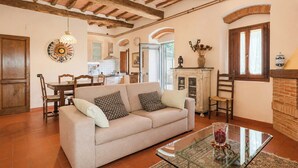 A living room with a sofa, a glass coffee table, and a fireplace. - Independent villa among Chianti vineyards (Greve in Chianti)
