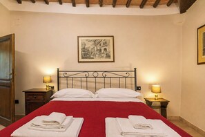 A hotel room with a bed, two bedside tables with lamps, a door, and a framed picture on the wall. - Independent villa among Chianti vineyards (Greve in Chianti)