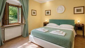 A bedroom with a bed, two bedside tables with lamps, a window with curtains, and framed pictures on the wall. - Independent villa among Chianti vineyards (Greve in Chianti)