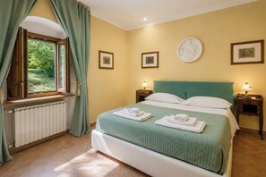 A bedroom with a bed, two bedside tables with lamps, a window with curtains, and framed pictures on the wall. - Independent villa among Chianti vineyards (Greve in Chianti)