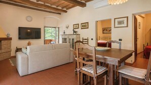 A living room with a sofa, dining table, chairs, a TV, and a fireplace. - Independent villa among Chianti vineyards (Greve in Chianti)