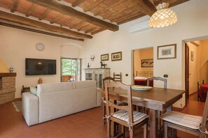 A living room with a sofa, dining table, chairs, a TV, and a fireplace. - Independent villa among Chianti vineyards (Greve in Chianti)
