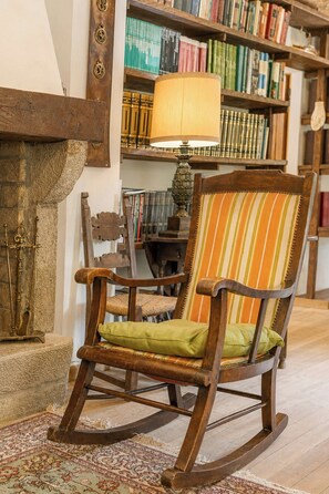 A rocking chair with a striped cushion in a room with a bookshelf and a lamp. - Independent villa among Chianti vineyards (Greve in Chianti)