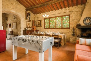 A room with a foosball table, a dining table set for four, a fireplace, and stone walls. - Independent villa among Chianti vineyards (Greve in Chianti)