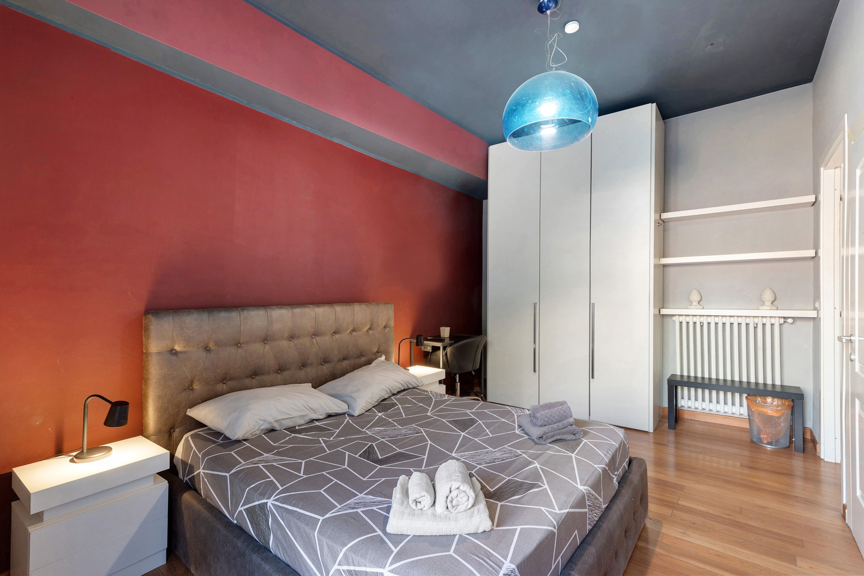 Un dormitorio moderno con cama, mesitas de noche, armario e iluminación colgante.