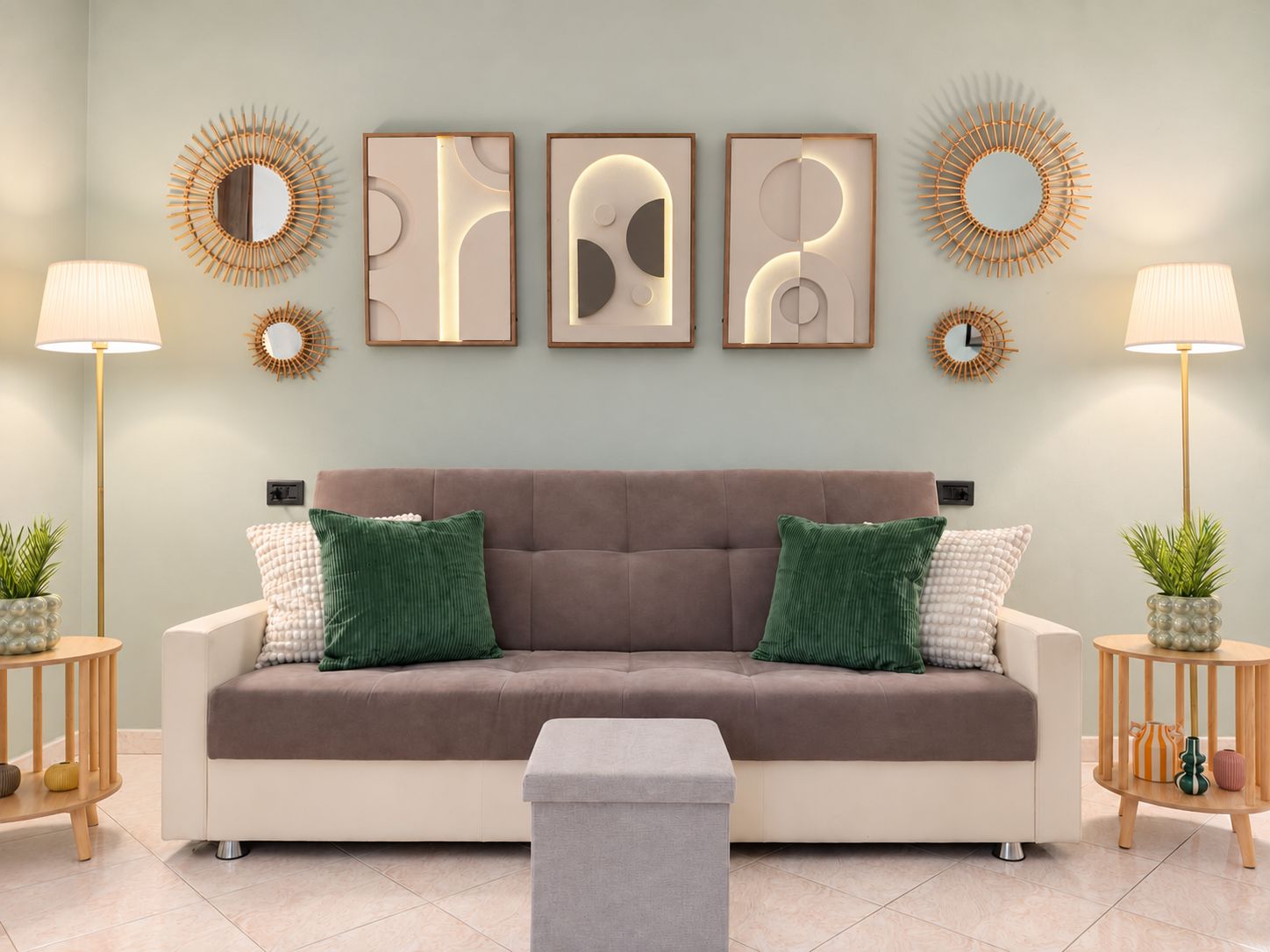 Un soggiorno moderno con un divano beige, cuscini verde e bianchi, un poggiapiedi grigio e opere d'arte alle pareti.