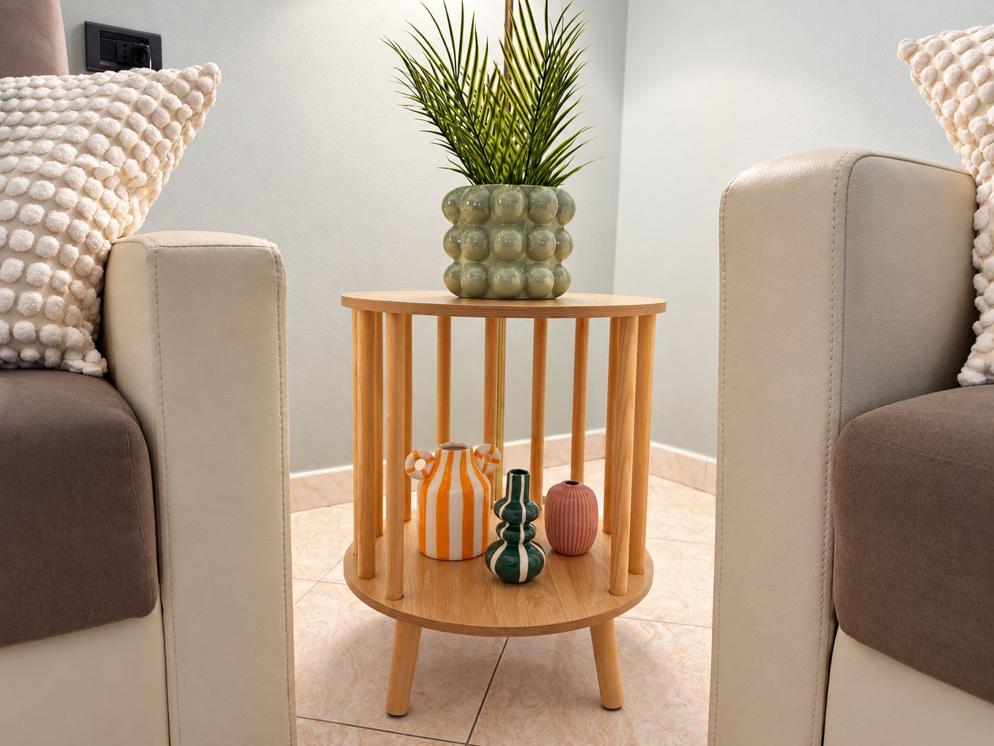 Ein modernes Wohnzimmer mit zwei beigen Sofas, einem Holztisch mit Dekoration und einer Zimmerpflanze.