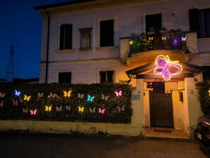 Un edifici amb un rètol de papallona de neó sobre l'entrada, una entrada tancada per una porta i un cotxe estacionat.
