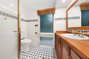 A bathroom with a toilet, a shower, and a sink with a mirror above it. - Charming Family Home | Pool & Entertainer's Deck (Carlingford)