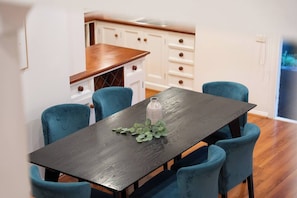 A dining area with a dark wooden table, four blue chairs, and a vase with greenery. - Charming Family Home | Pool & Entertainer's Deck (Carlingford)