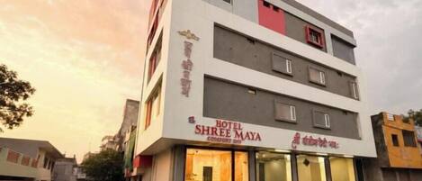 A multi-story hotel with a sign reading 'HOTEL SHREE MAYA' and a staircase leading to the entrance.