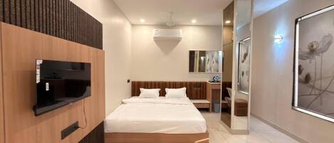 A modern bedroom with a bed, a mounted TV, a mirror, and a ceiling fan.