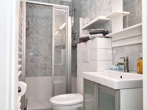 A modern bathroom with a glass shower enclosure, a toilet, a sink with a mirror, and a towel rack. - Ankertied: Your cozy vacation apartment in Büsum, near the sea (Büsum)