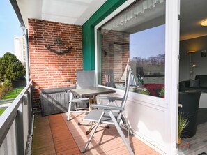 A balcony with a table and chairs, a brick wall, and a view of the outside. - Ankertied: Your cozy vacation apartment in Büsum, near the sea (Büsum)