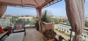 Un balcon avec vue sur la ville, une table avec une chaise et des plantes en pot.