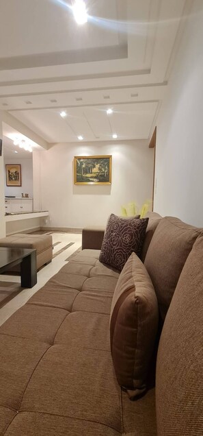 Ein modernes Wohnzimmer mit einem Ecksofa, einem Couchtisch und einem Gemälde an der Wand.