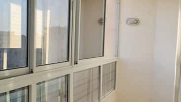 Un pasillo con ventanas amplias, piso de baldosas y una puerta con manija.