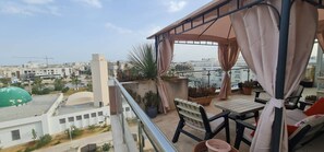 A balcony with a table and chairs, potted plants, and a view of the cityscape. - Luxurious 3-bedroom Apartment in Heart of Tunis (Tunis)