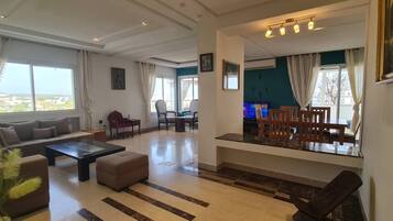 A spacious living area with a sofa, coffee table, and dining set.