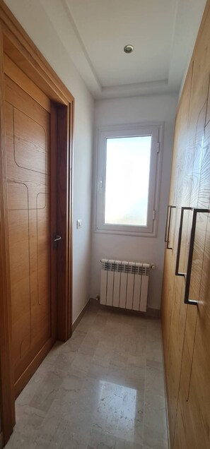Ein Flur mit Holztür, Heizkörper und Fenster.