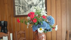 A dining table with a vase of flowers, a plate, a glass, and cutlery. - Guesthouse Room for 2 or 3 – Breakfast Included (Priziac)