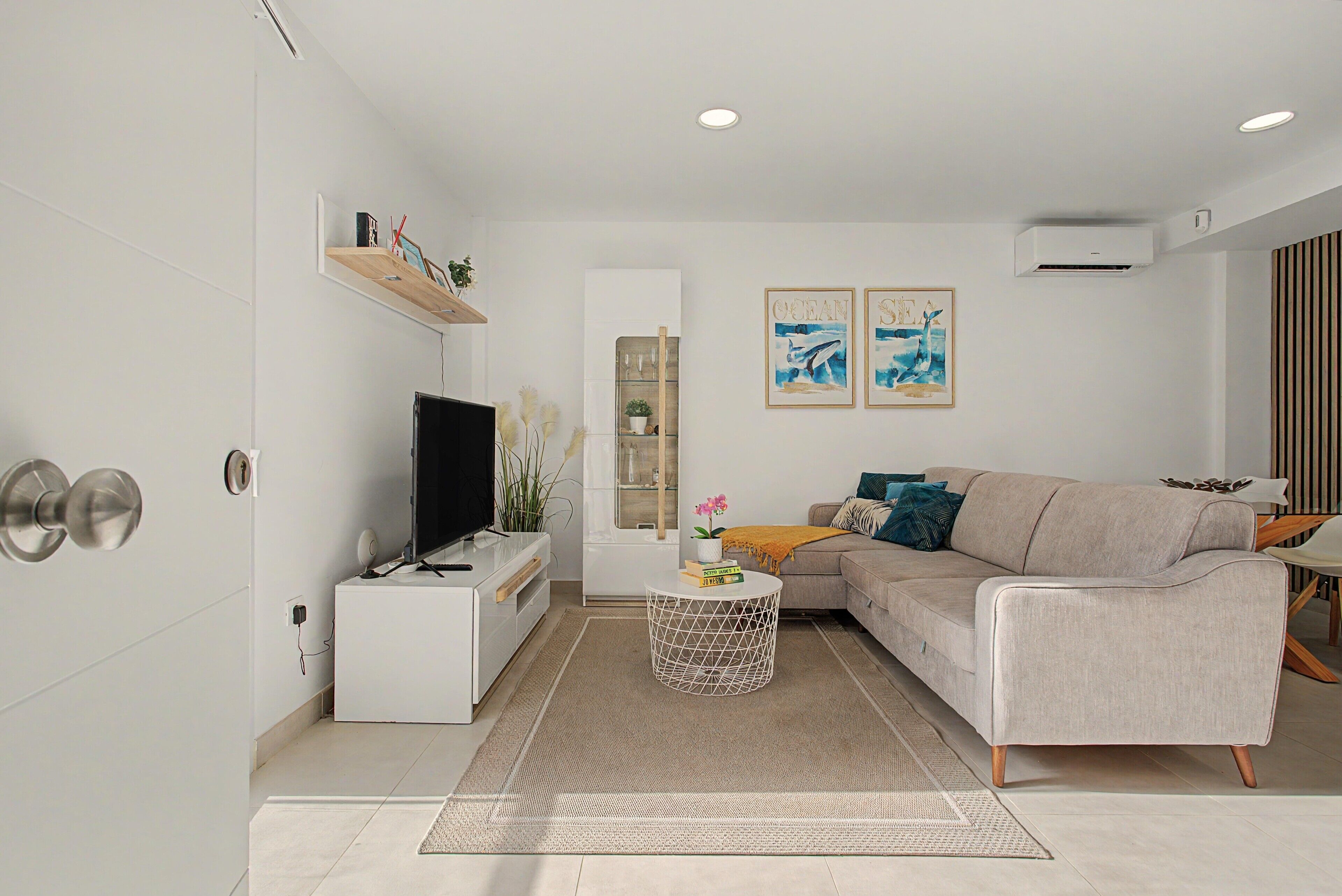 Una sala de estar moderna con televisor de pantalla plana, sofá, mesa de centro y objetos decorativos.
