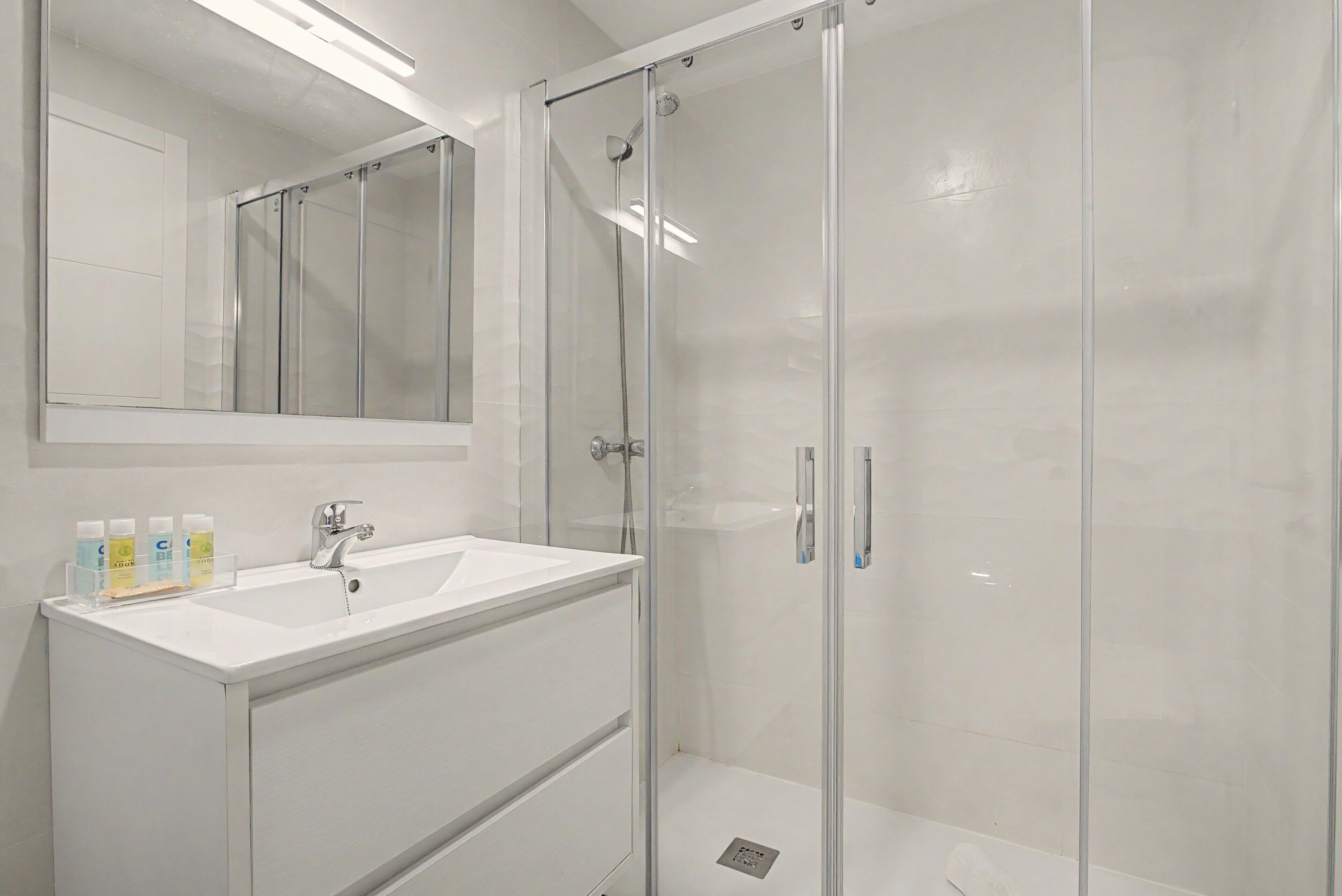 A modern bathroom with a glass-enclosed shower, a white sink, and a mirror above the vanity.
