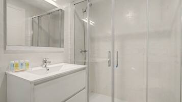 A modern bathroom with a glass-enclosed shower, a white sink, and a mirror above the vanity.