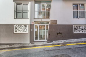 Un edificio con entrada numerada, señal de alarma contra incendios y portero automático.