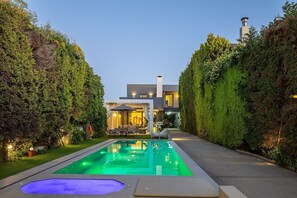 A modern house with a swimming pool, surrounded by well-maintained hedges, and a patio area with outdoor furniture. - Hestia Grey Barefoot Escape 100m From Beach (Rethymno)