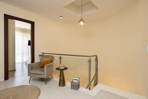 A modern living room with a grey armchair, a small round table, and a glass railing. - Hestia Grey Barefoot Escape 100m From Beach (Rethymno)