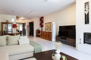 Un salon moderne comprenant un canapé, une table basse, un téléviseur et un coin repas avec des chaises et une table.