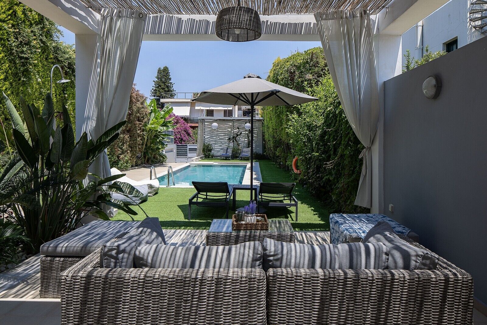 A private pool area with a lounge chair, umbrella, and a view of a building in the background.