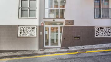 Un edificio con entrada numerada, señal de alarma contra incendios y portero automático.