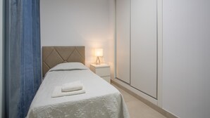 A hotel room with a bed, a nightstand, a lamp, and a wardrobe. - Vacation Apartment 'Brisa A. Apto En El Médano' with Wi-Fi and Air Conditioning (El Médano)