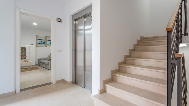 A modern interior with a staircase, a door leading to a living area, and a wall-mounted elevator. - Vacation Apartment 'Brisa A. Apto En El Médano' with Wi-Fi and Air Conditioning (El Médano)