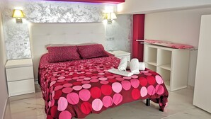 A bedroom with a bed, bedside tables, a wardrobe, and a wall-mounted shelf. - Studio Apartment 'Ofis - Estudio Morado' with Wi-Fi and Air Conditioning (Conil de la Frontera)
